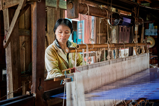 A Myanmar woman weaving fabric with fibre from lotus stems using a tradition loom.