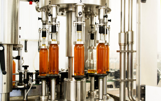 Bottles of wine being filled by a machine on a bottling line specialising in wine and cider