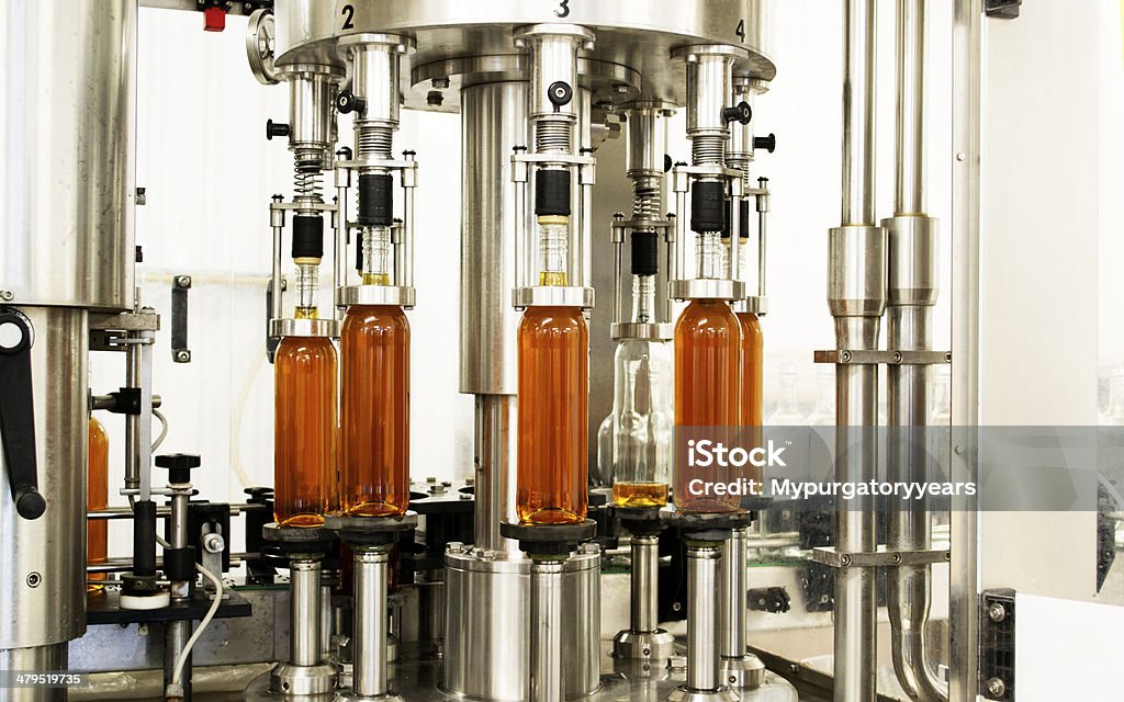 Wine production Bottles of wine being filled by a machine on a bottling line specialising in wine and cider Machinery Stock Photo