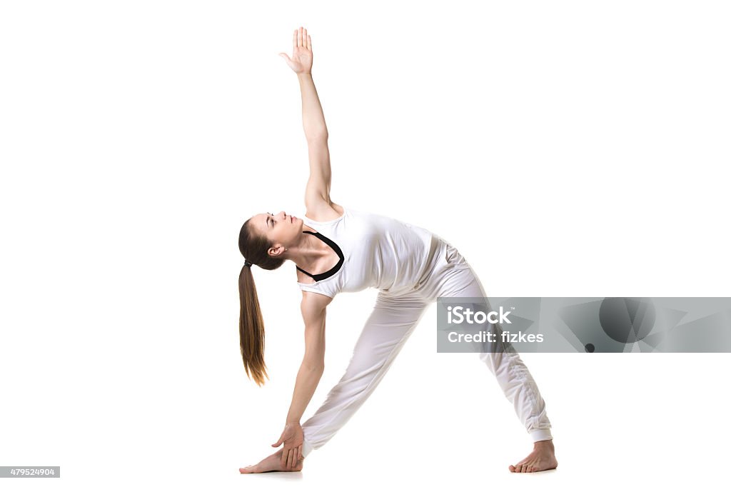 Yoga Trikonasana pose Beautiful fitness model practices yoga or pilates, standing in Triangle yoga pose, Trikonasana, stretching exercise, front view 2015 Stock Photo