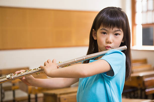 istock Cute pupil playing flute in classroom 479526656
