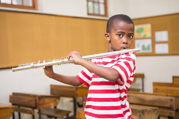 istock Cute pupil playing flute in classroom 479526670