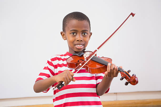 istock Happy pupil playing violin in classroom 479526872