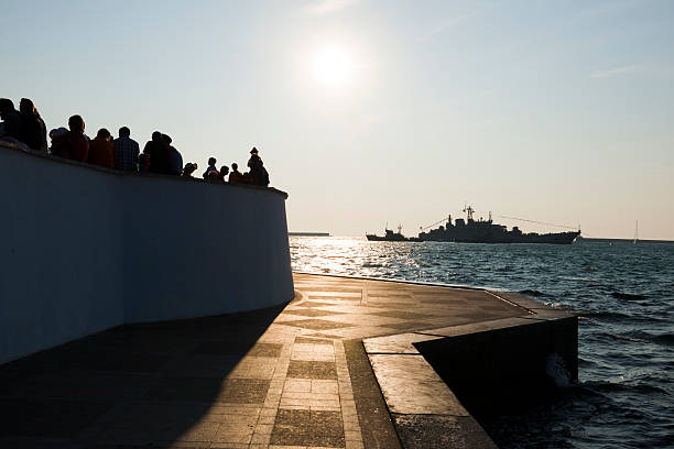 The sun begins to set over people and a Ukrainian naval vessel on a summer day in Sevastopol, Crimea.