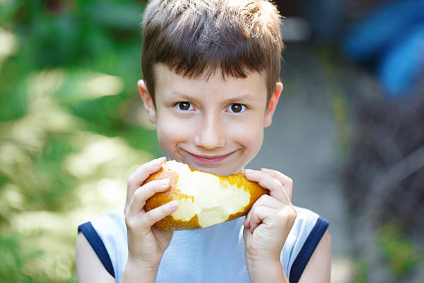 istock Little caucasian boy eating pear outdoor 479546174