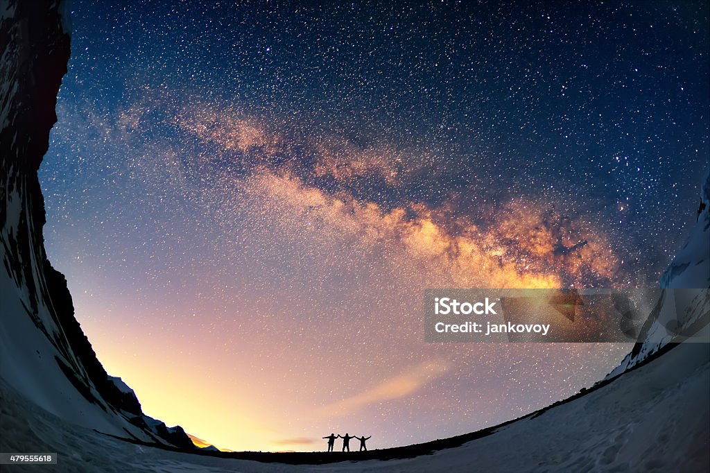 Knocking on heaven's door Silhouettes of the people standing together holding hands against the Milky Way in the mountains. Family Stock Photo