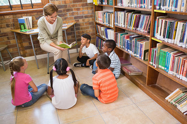 istock Cute pupils and teacher having class in library 479557632