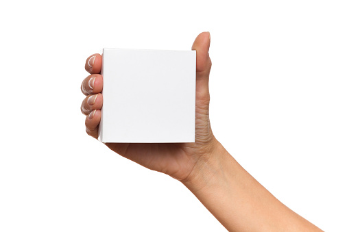 Close up of woman's hand holding white carton box. Studio shot isolated on white.
