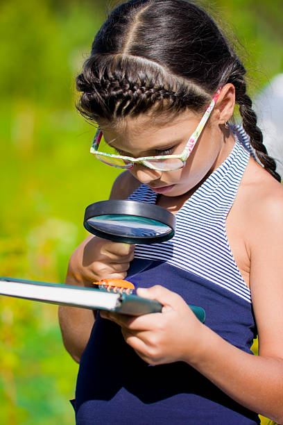 istock girl looking through magnifying glass on beetle 479567961