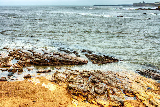 Rocks off the coast of Cullercoats/Tynemouth with North Shields lighthouse in the distance.  Image has been enhanced with HDR software.