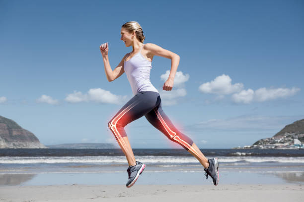 Highlighted leg bones of jogging woman on beach stock photo