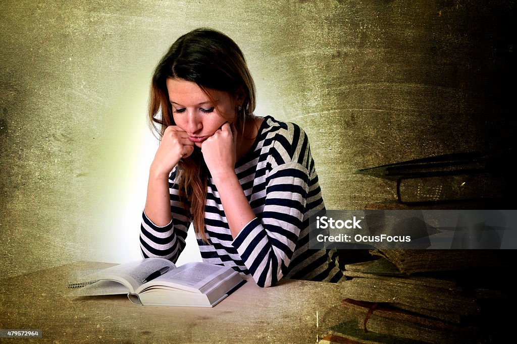 young stressed student girl studying and preparing MBA test exam young stressed student girl studying pile of books on library desk preparing MBA test or exam in stress feeling tired and overwhelmed in youth education concept grunge messy background style 2015 Stock Photo