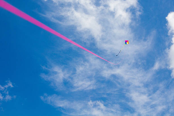 istock Colorful kite with pink kitestring under a blue cloudy sky 479573612