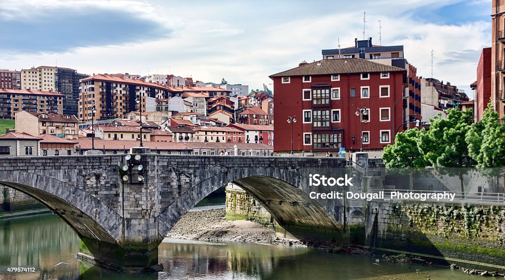 Bilbao Neighbourhood Houses Looking Across Nervión River Bilbao houses seen along the Nervión River, or Bilbao Estuary. The San Antón Bridge can be seen in the foreground . It is the oldest bridge in Bilbao and links the neighborhoods La Vieja and Casco Viejo. Many houses and high rise apartments can be seen in the background behind the tree lined river. Bilbao Stock Photo
