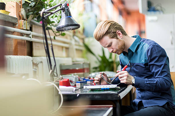 joven hombre atractivo soldadura de una placa de circuito - industry portrait production line factory fotografías e imágenes de stock