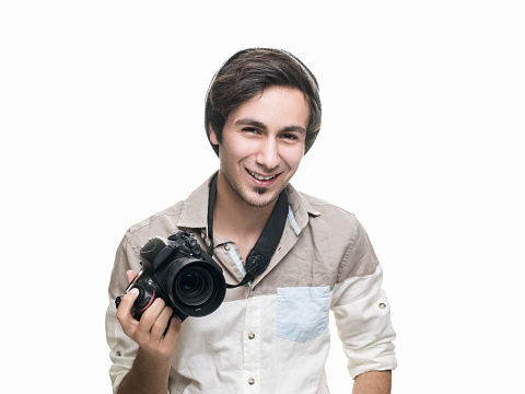 Smiling teenage boy holding a SLR camera and looking at camera with positive facial expression. Horizontal composition. Image taken in studio with medium format Hasselblad H5D and developed from Raw format.