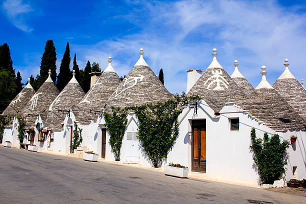 Trulli dwellings in Puglia, Italy Row of typical trulli houses in Alberobello, Puglia, Italy. Traditional symbols are painted on the conical roofs. A trullo is a traditional Apulian stone dwelling with the style of construction is specific to Itria Valley. murge photos stock pictures, royalty-free photos & images