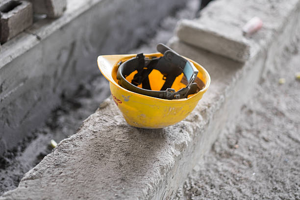 Hard Hat sitting on Rough Concrete Yellow hard hat sitting on a concrete ledge in a constrcution site. The hard hat is obviously used with some wear. abandoned stock pictures, royalty-free photos & images