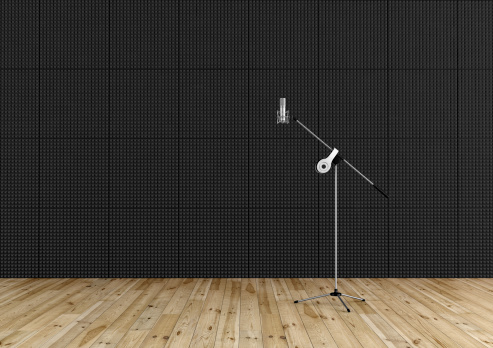 Professional microphone in a recording studio with black acoustic panel and wooden floor - rendering