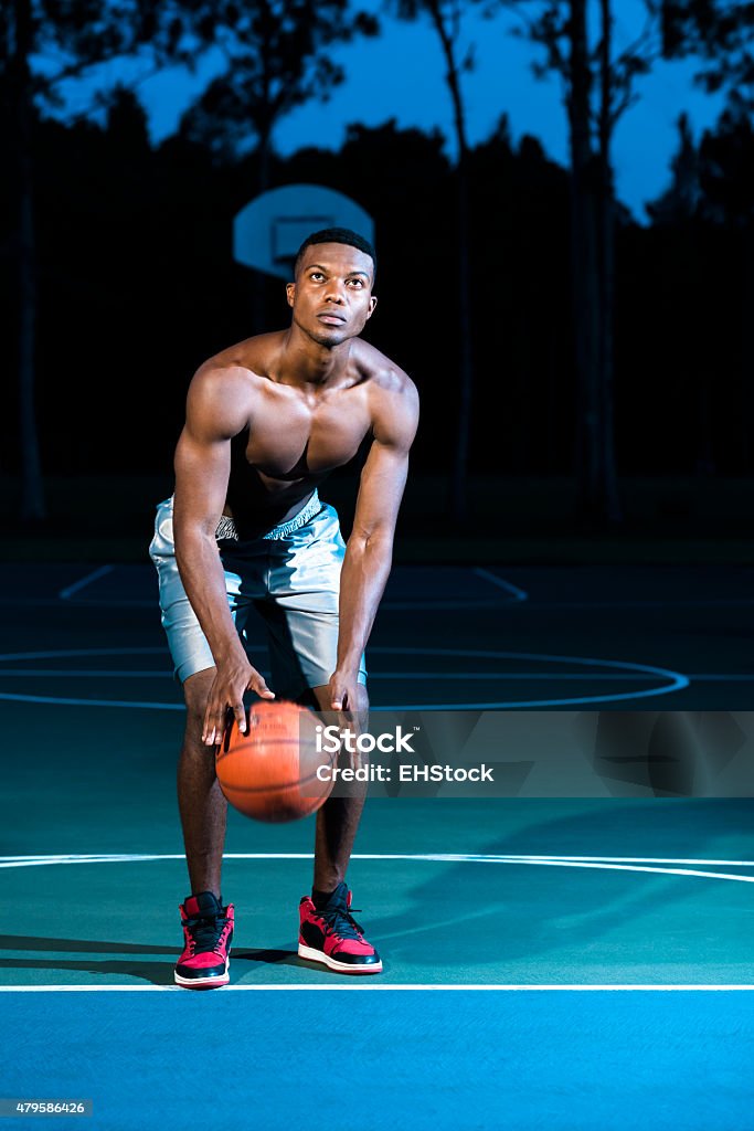 Basketball Player Free Throw Basketball player concentrating on hoop from free throw line.  Player is in blue hoody and evening sky is deep blue. Basketball - Ball Stock Photo