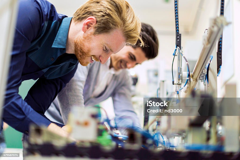 Two young handsome engineers working on electronics components Two young handsome engineers working on electronics components and fixing broken chips Engineer Stock Photo