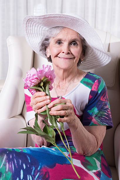 active female senior smelling a flower