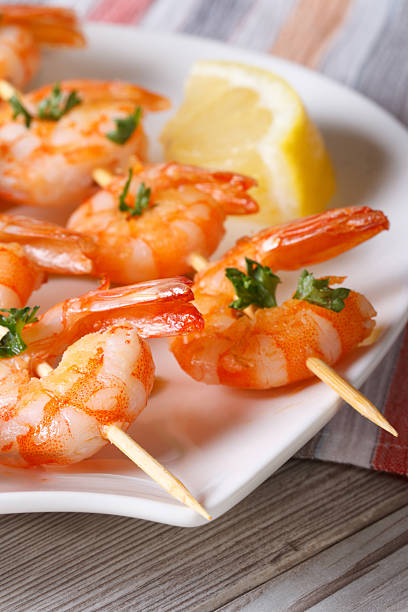 istock Delicious fried shrimp on wooden skewers macro. Vertical 479590790
