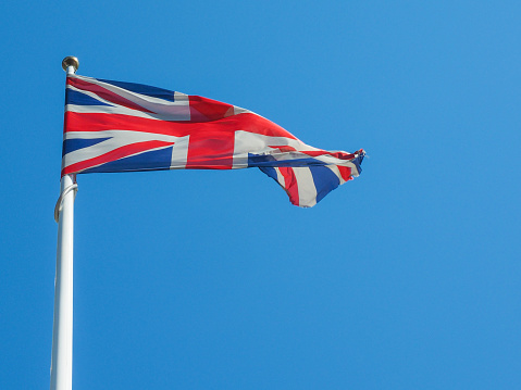 The national flag of United Kingdom, Europe floating in the wind over blue sky