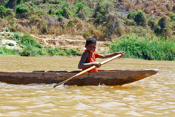 istock Young Malagasy african boy rowing traditional canoe on river 479598468