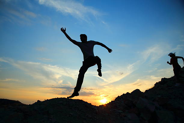 istock Silhouettes of two people jumping 479599556