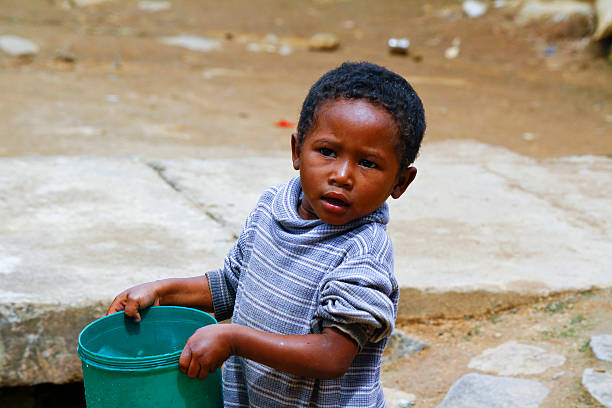 istock Poor malagasy boy carrying plastic water bucket - poverty 479607016