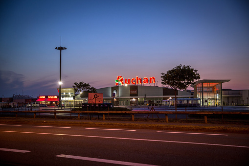 Coquelles, France - June 11, 2015: Evening image of the Auchan supermarket chain building at Coquelles in France. Other company brands and buildings are also pictured