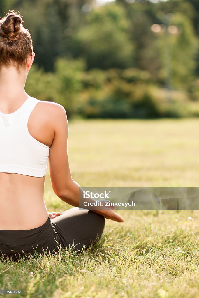 Pleasant young woman practicing yoga Enjoy the silence. Pleasant young lady practicing yoga while sitting on the grass and having good time. 2015 Stock Photo