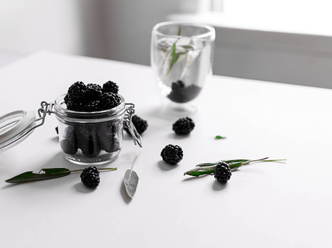 blackberries in a jar with glass of water on a table