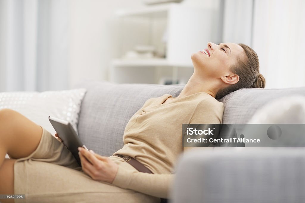relaxed young woman sitting on sofa with tablet pc Relaxed young woman sitting on sofa with tablet pc Adult Stock Photo