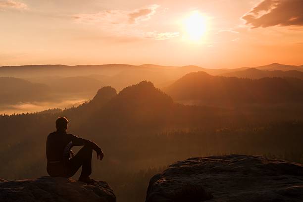 istock Tourist in wind jacket sit on rock watch to Sun 479631064
