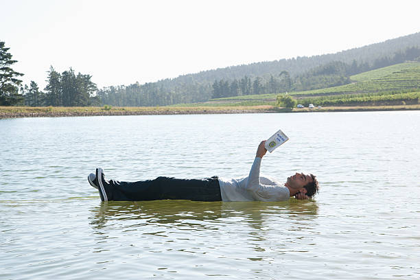 homem deitado para baixo na água lendo livro - andando em água - fotografias e filmes do acervo