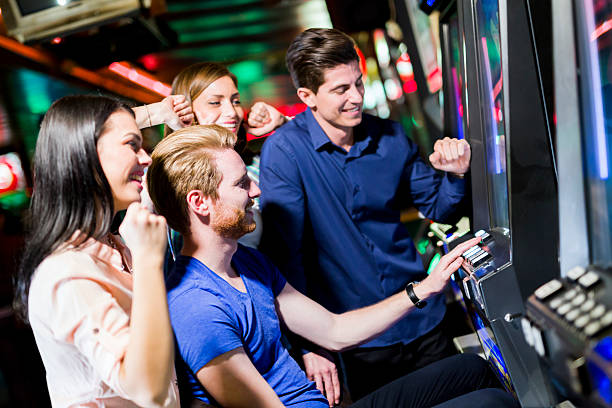 amis jouant un jeu dans le casino de machines à sous et des machines - amusement arcade photos et images de collection