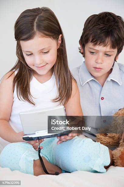 A Boy Watching Girl Play A Handheld Game Stock Photo - Download Image Now - 60-64 Years, 60-69 Years, 8-9 Years