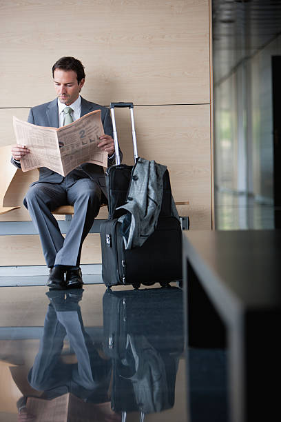 empresario con una maleta leyendo periódico - airport newspaper travel business travel fotografías e imágenes de stock