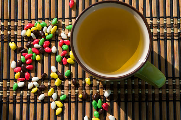cup of tea and colorful candy on a bamboo mat on the window sunlight