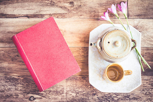 istock Tea cups with teapot with red book on old wooden. 479650412