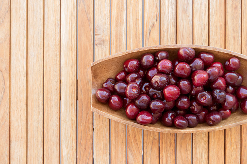 Bowl of sweet cherries on wooden table