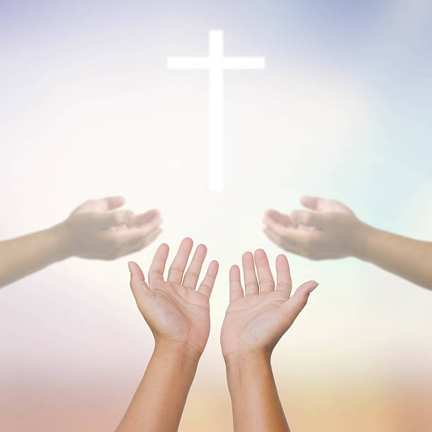 istock open hands praying the cross on blur sky background. 479656838