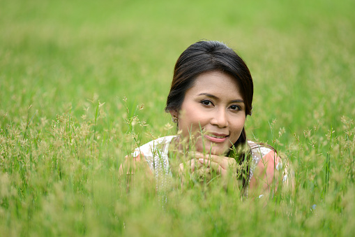 Young woman smiling and lying down on grass 