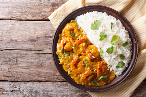 Shrimps in curry sauce and rice on a plate. horizontal view from above