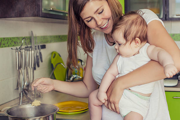 madre de una mujer con un bebé prepara la comida - stereotypical housewife little girls family domestic kitchen fotografías e imágenes de stock