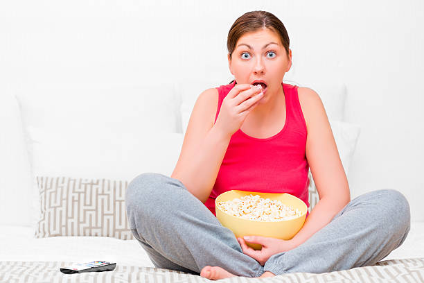 istock female attentively watching TV and eating popcorn 479681268