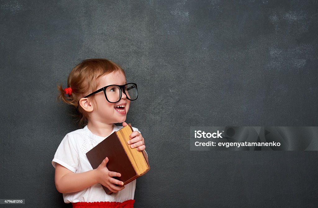 Glückliche Mädchen im Schulmädchen mit Buch von blackboard - Lizenzfrei Schreibtafel Stock-Foto