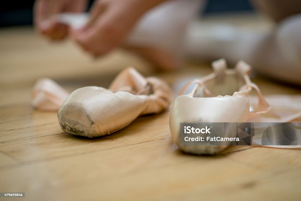 Ballet Shoes A young ballet dancer sitting on the floor with her shoes in-front of her. 2015 Stock Photo